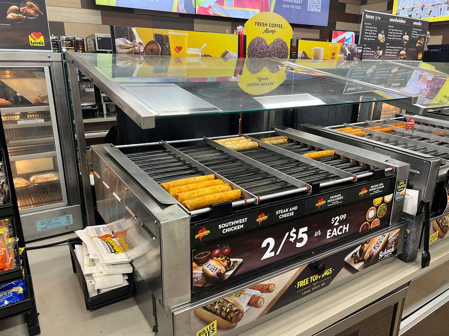 Commercial roller grill with hot food and sneeze guard in a convenience store foodservice program