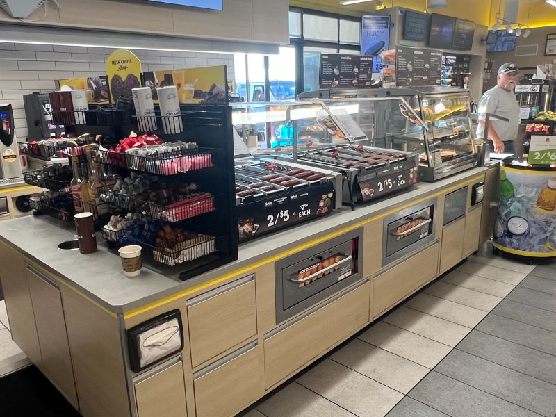 Convenience store foodservice destination featuring commercial roller grills, coffee, and grab-and-go offerings