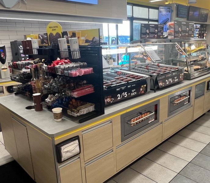 Convenience store foodservice destination featuring commercial roller grills, coffee, and grab-and-go offerings